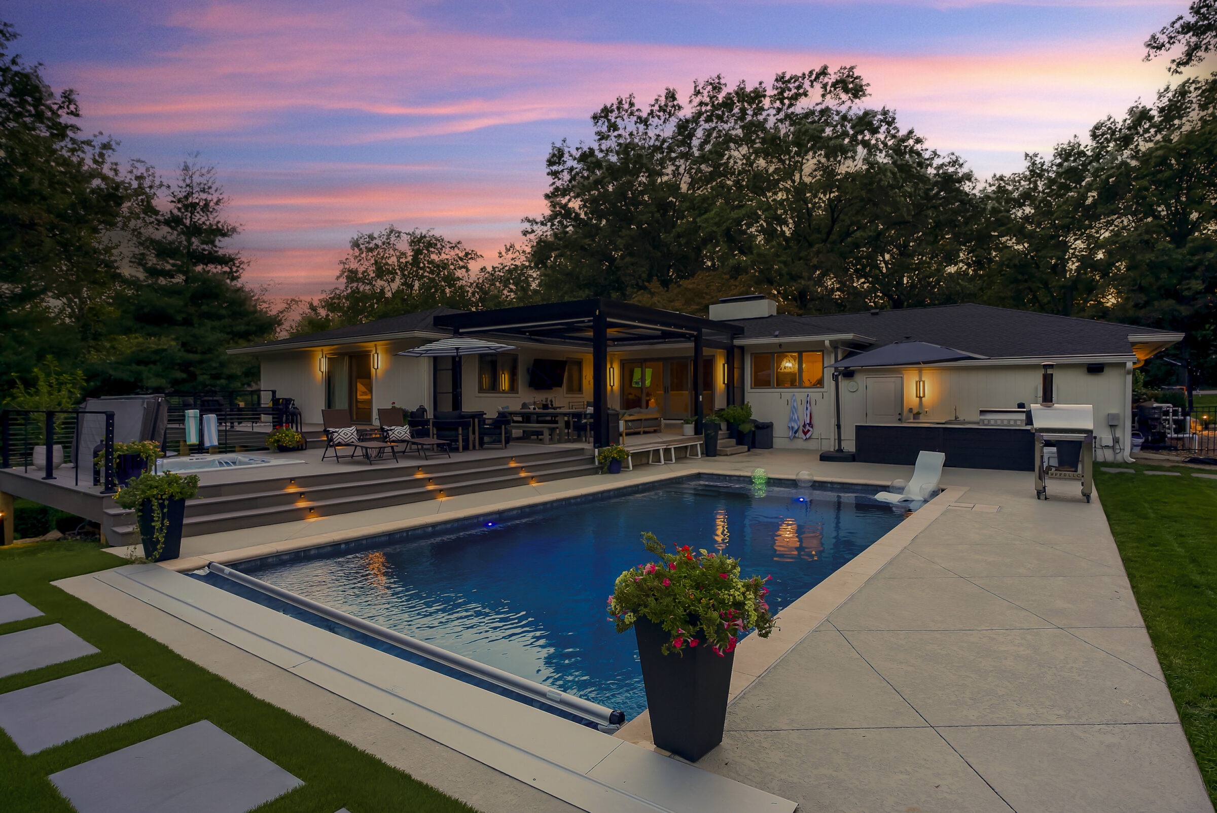 A modern house with a swimming pool at sunset, surrounded by lush trees and outdoor seating, offering a serene and elegant atmosphere.